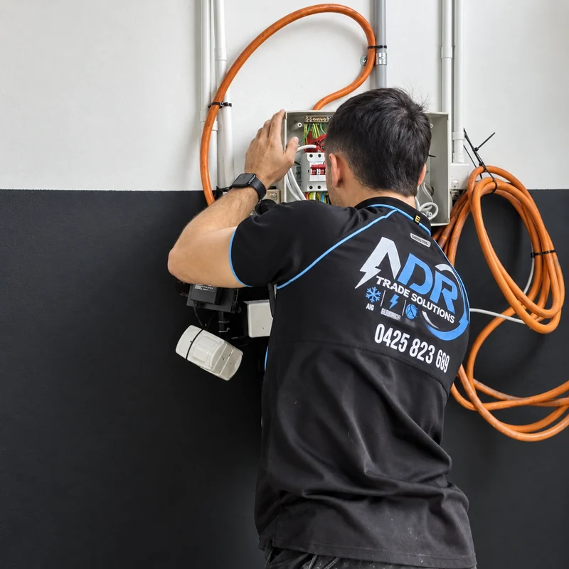 An NDR electrician working at an open electrical switchboard